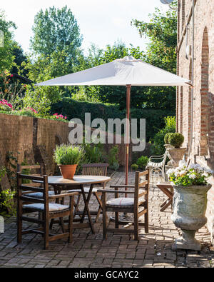 Meubles en teck et des urnes en pierre sur terrasse avec parasol sunny briqué Banque D'Images