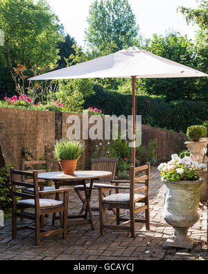 Meubles en teck et des urnes en pierre sur terrasse avec parasol sunny briqué Banque D'Images