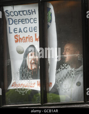 Un homme présente une affiche SDL dans la fenêtre du bar Jenny Ha sur le Royal Mile, à Édimbourg. Les manifestants antifascistes ont ciblé ce qu'ils ont dit, c'est un rassemblement de la Ligue de défense écossaise d'extrême-droite (SDL). Les manifestants ont déclaré que des membres du SDL se trouvaient à l'intérieur du bar de Jenny Ha et se sont engagés à rester dans la région jusqu'à ce qu'ils quittent la ville. Banque D'Images