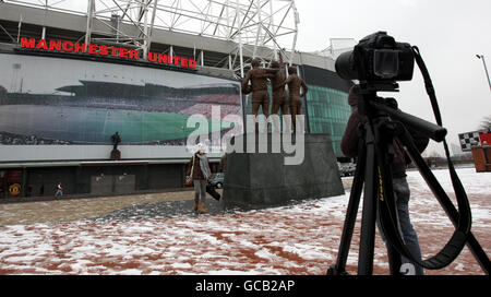 Une affiche à l'extérieur du stade Old Trafford de Manchester United célébrant les 100 ans du stade Old trafford est également représentée sur la photo : la statue de Denis Law, Sir Bobby Charlton et George Best et la statue de Sir Matt Busby (arrière-plan central) Banque D'Images