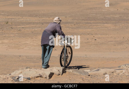 Paysan unique au Maroc desert poussant un vélo. Banque D'Images