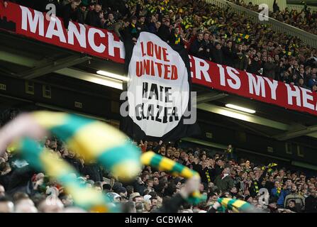 Les fans de Manchester United branle des foulards jaunes et verts dans le Se tient et défure une bannière disant Love United Hate Glazer Banque D'Images