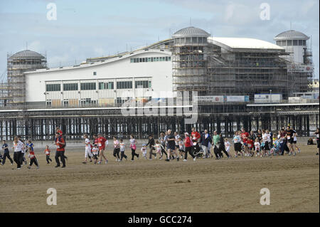 Les coureurs passent devant le Grand Pier de Weston-super-Mare lorsqu'ils participent à la course caritative In Sainsbury's Sport relief Mile. Banque D'Images
