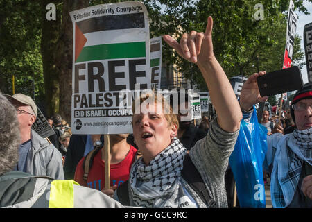 Londres, Royaume-Uni. 8 juillet 2016. Un manifestant à Downing St fait un geste au petit groupe de manifestants pro-Israël qui vague des drapeaux israéliens pour protester par plusieurs centaines d'appels à mettre fin à près de dix ans d'Israël siège de Gaza, et la fin de la UK's commerce des armes avec Israël. Il y a eu trois grandes agressions militaires par les forces militaires d'Israël sur Gaza au cours des 8 dernières années, ce qui a fait des milliers de morts palestiniens, et faire de la petite région, accueil à 1,8 million de personnes, principalement des réfugiés et de leurs familles pratiquement inhabitable. Le blocus empêche les matériaux nécessaires pour la reconstruction atteindre Banque D'Images