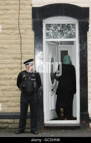 Une femme entre dans la porte d'entrée alors qu'un policier se tient à l'extérieur du domicile d'Oldham, dans le Grand Manchester, de Sahil Saeed, cinq ans, qui a été enlevé pendant ses vacances au Pakistan il y a près de deux semaines et qui, selon le Haut-commissariat britannique, a été bien situé. Banque D'Images