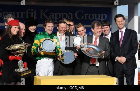 Le jockey Tony McCoy (cinquième à gauche), l'entraîneur Nicky Henderson (sixième à gauche) et le propriétaire John McManus (troisième à droite) célèbrent la victoire du Smurfit Kappa Champion Hurdle Challenge Trophy Trophy avec Binoculaire Banque D'Images