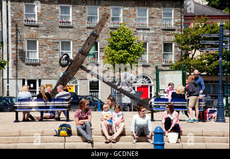 Les gens assis sur les marches et bancs en ville avec une grande ancre sur l'affichage, Bantry, dans le comté de Cork, Irlande Banque D'Images