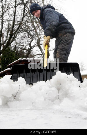 Printemps météo mars été.Un homme déneigement au club de golf de Lenzie en Écosse après une chute de neige fraîche la nuit. Banque D'Images