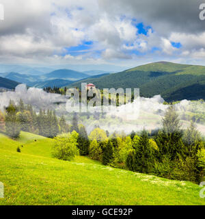 Paysage d'été. Village sur le flanc de la montagne avec la forêt dans le brouillard Banque D'Images