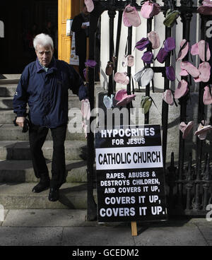 Un homme (nom inconnu) passe des chaussures pour enfants accrochées dans des rampes par des survivants d'abus commis à la Messe du dimanche de Pâques à la St Mary's Pro-Cathedral à Dublin.La pression monte sur l'Église catholique depuis un rapport de bombardement en novembre qui détaille des décennies d'abus d'enfants en Irlande et a constaté que des prêtres pédophiles étaient protégés par des pairs et des responsables. Banque D'Images