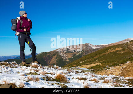 Female Hiker énergique d'un séjour sur terrain enneigé et l'observation d'une vue panoramique sur la montagne Banque D'Images