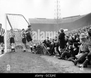 Le gardien de but de Newcastle United, Ronnie Simpson, rejoint presque les spectateurs pour récupérer le ballon derrière son but, où les foules se sont rassemblées au bord du terrain. Banque D'Images