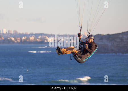 Un homme vole son parapente le long de la clifftops. Le deltaplane est aussi populaire ici, sur les plages du nord de Sydney péninsule. Banque D'Images