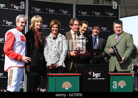 Le jockey Ruby Walsh (à l'extrême gauche), le propriétaire Andy Stewart (au centre) et l'entraîneur Paul Nicholls (à l'extrême droite) posent avec leurs trophées après que leur cheval Big Buck's a remporté l'obstacle de Liverpool des partenaires du BGC. Banque D'Images