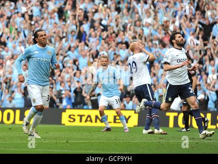 Carlos Tevez de Manchester City (à gauche) célèbre après avoir obtenu l'égaliseur De la pénalité comme Aston Villa joueurs James Collins (2e à droite) et Carlos Cuellar (à droite) se sont déprimés Banque D'Images