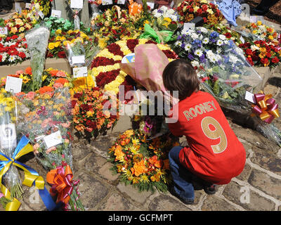 Un jeune fan de football rend un hommage floral au Valley Parade Memorial aux victimes de la catastrophe du feu de la ville de Bradford après le service de commémoration du 25e anniversaire de la place du Centenaire, à Bradford. Banque D'Images