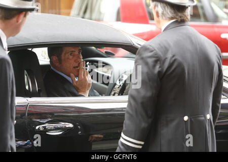 Dale Winton, présentateur de télévision, s'enrôle dans l'aide des portiers de Claridge tout en fumant une cigarette lorsqu'il arrive à Claridge's, dans le centre de Londres, pour le mariage de David Walliams et Lara Stone. Banque D'Images