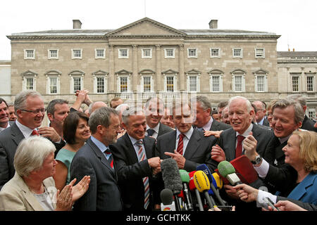 Le chef de fine Gael Enda Kenny (au centre, cravate à rayures rouges) sourit alors qu'il secoue la main de Richard Bruton (au centre à gauche) sur la plinthe de la Maison Leinster, après avoir remporté le vote lors d'une réunion parlementaire cruciale pour la direction du parti. Banque D'Images