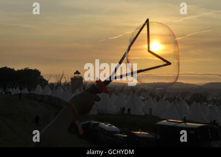 Un révélateur souffle des bulles géantes au coucher du soleil au Glastonbury Festival 2010, digne Farm, Pilton, Somerset. Banque D'Images