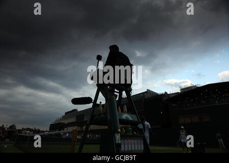 L'arbitre garde un œil sur le ciel orageux au-dessus de Wimbledon pendant le match mixte de doubles entre Julian Knowle en Autriche et Yaroslava Shvedova au Kazakhstan et l'appariement de Philipp Marx et Andrea Petkovic en Allemagne Banque D'Images