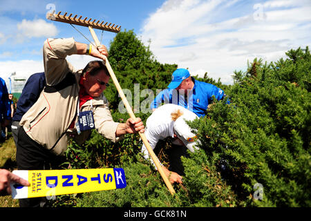 Marcel Siem (au centre), en Allemagne, est aidé par des marshals qui s'occupe de sa balle perdue dans un buisson de gorge sur le trou 14 au cours de la quatrième manche du Championnat Open 2010 à St Andrews, Fife, Écosse Banque D'Images