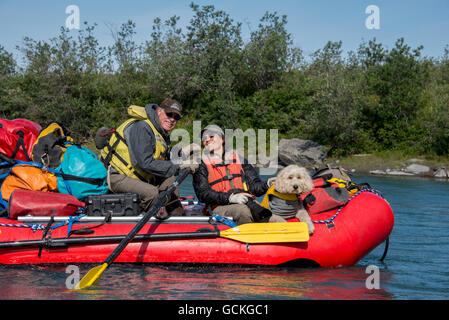 Couple et leur Golden Doodle assis dans Un radeau dans le soleil le long de la fourche de marais de la rivière Canning dans la réserve naturelle nationale de l'Arctique, ... Banque D'Images