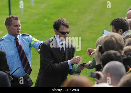 Un garde de sécurité demande à l'entraîneur de course irlandais Aidan O'Brien de quitter la piste pendant qu'il signe des autographes pour les fans pendant le festival Ebor à l'hippodrome de York. Banque D'Images