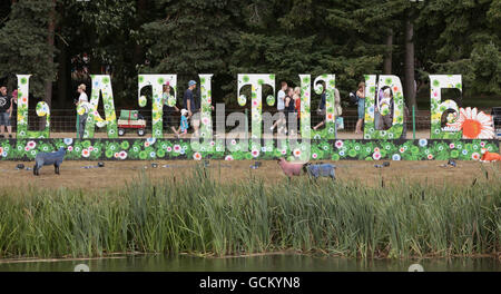 Les festivaliers marchent devant un grand panneau « Latitude » au festival Latitude, qui a lieu à Henham Park à Southwold, Suffolk. Banque D'Images