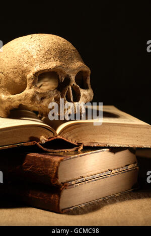 Concept spectaculaire. Crâne humain sur de vieux livres sur fond sombre Banque D'Images