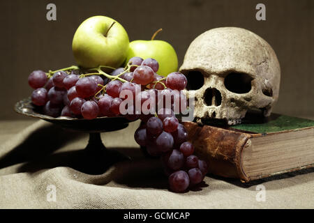 Concept de la mort. Crâne humain sur de vieux livres près de coupe de fruits Banque D'Images