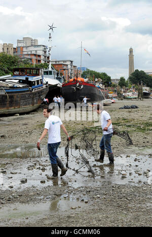 Des bénévoles de Thames21, la principale association caritative de London sur les voies navigables, aident à nettoyer les préphores de la Tamise à Brentford. La zone a une accumulation de sacs en plastique, chariots à provisions, cônes de circulation, pneus et autres déchets. Banque D'Images