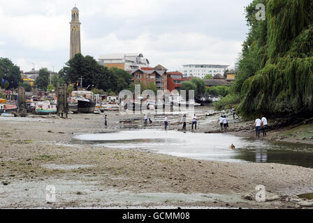 Des bénévoles de Thames21, la principale association caritative de London sur les voies navigables, aident à nettoyer les préphores de la Tamise à Brentford. La zone a une accumulation de sacs en plastique, chariots à provisions, cônes de circulation, pneus et autres déchets. Banque D'Images