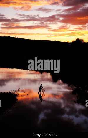 Un pêcheur solitaire tente sa chance d'attraper quelques truites dans le cadre tranquille de la rivière Coquet près de Rothbury, Northumberland, au coucher du soleil hier soir. Banque D'Images