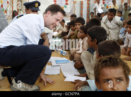 Nick Clegg, vice-premier ministre britannique, parle à un garçon dans une salle scolaire improvisée dans un camp pour les personnes déplacées par les inondations, près de la ville de Sukkur, lors d'une visite dans le sud du Pakistan. Banque D'Images