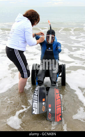 Le nageur français sans limite Philippe Croizon est aidé dans la mer par la membre de l'équipe Valerie Carbonnel lors d'une session d'entraînement à Folkestone, Kent, avant sa tentative plus tard cette semaine de devenir la première personne sans limite à nager la Manche de Folkestone à la France sur une distance de 21 miles. Banque D'Images