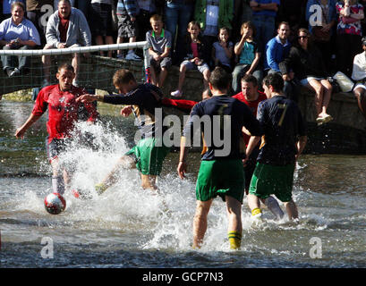 Joueurs lors du match annuel de football de la rivière Windrush qui traverse le centre de Bourton-on-the-Water, à Gloucestershire. Banque D'Images