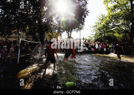 Joueurs lors du match annuel de football de la rivière Windrush qui traverse le centre de Bourton-on-the-Water, à Gloucestershire. Banque D'Images