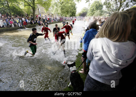 Joueurs lors du match annuel de football de la rivière Windrush qui traverse le centre de Bourton-on-the-Water, à Gloucestershire. Banque D'Images