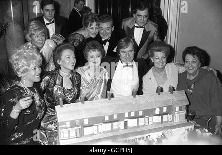 Les membres de la troupe de l'opéra de savon d'ITV Coronation Street, bondés autour d'une réplique de gâteau de la rue à la célébration pour marquer son 25ème anniversaire à l'hôtel Dorchester. Première rangée, de gauche à droite, Julie Goodyear, Eileen Derbyshire, Thelma Barlow, William Roache, Jean Alexander et Betty Driver. Rangée arrière, de gauche à droite, Liz Dawn, Nigel Pifaro, Anne Kirkbride, Bryan Mosley et Bill Tarmey. Banque D'Images