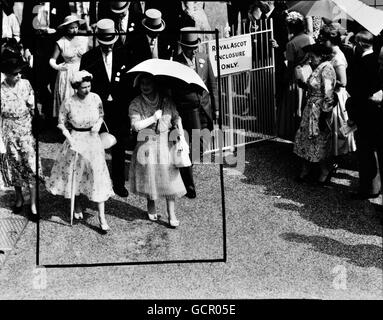 La reine mère lève son parasol contre le soleil flamboyant, mais le store de la reine est fusillé alors qu'ils marchent jusqu'au paddock lors de la rencontre de course de Royal Ascot le 13 juillet 1955. La robe en soie blanche de la Reine est recouverte d'un chapeau de pétales de fleurs blanches. La robe de sa mère est en pieu bleu jacinthe, portée avec un grand chapeau d'organdie bleu et blanc Banque D'Images