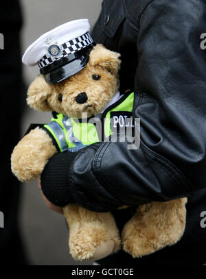 Un jeune garçon tient à Teddy vêtu comme policier de la circulation pendant le service de police Métropolitaine annuel du Collège de police d'Hendon, dans le nord de Londres. Banque D'Images