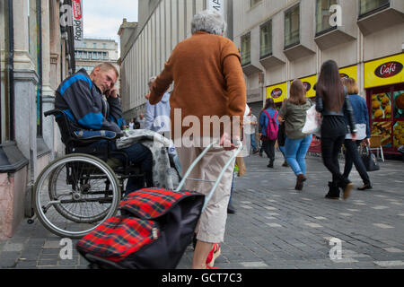 Aider les sans-abri handicapés mendiant assis en fauteuil roulant, reçu un don en argent par un passant à Liverpool, Merseyside, Royaume-Uni Banque D'Images