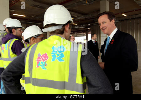 Le Premier ministre David Cameron parle aux apprentis ouvriers de la construction alors qu'il se rend pour la première fois sur le site du parc olympique à Stratford, dans l'est de Londres. Banque D'Images