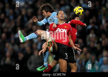 Rio Ferdinand (au centre) et Rafael Da Silva (à droite) de Manchester United se battent pour le ballon dans les airs avec David Silva (à gauche) de Manchester City Banque D'Images