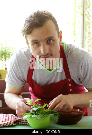 Salade de légumes cuisson Man (tomates, laitue, concombres) sur une planche en bois Banque D'Images