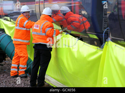 Le personnel de ScotRail ajuste la plinthe tandis que les soufflantes à gaz aident à dégivrer le train de roulement des trains, tandis que le nouveau ministre écossais des Transports Keith Brown utilise un spray de dégivrage « Kill Frost » qui empêche et facilite l'élimination de la glace du train de roulement d'un train lors d'une visite au dépôt Eastfield de ScotRail à Glasgow. Banque D'Images