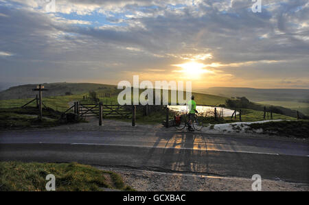 Un cycliste s'arrête ce matin pour admirer le lever du soleil au sommet de Ditchling Beacon, près de Brighton. Banque D'Images