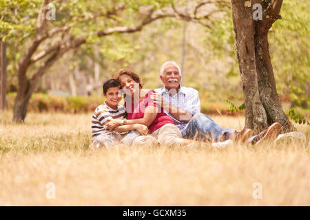 Les personnes âgées, en couple, une femme et un homme âgés. Une famille s'amusant avec papi et mamie hugging boy at picnic Banque D'Images