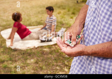 Les personnes âgées, en couple, une femme et un homme âgés en parc. Grand-père malade de prendre des médicaments sur ordonnance, médicaments, pilules pour les soins cardiaques Banque D'Images