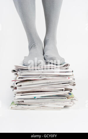 Homme debout sur un tas de vieux journaux Banque D'Images